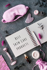 Text Best Skincare Products in notebook. Face massage roller, gua sha stone, essential oil,...