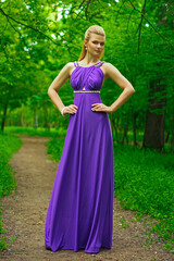 Obraz na płótnie Canvas blonde beautiful natural girl with blonde hair in a lilac dress in nature, in the park, in the garden by a tree, with makeup and hairstyle without a bra