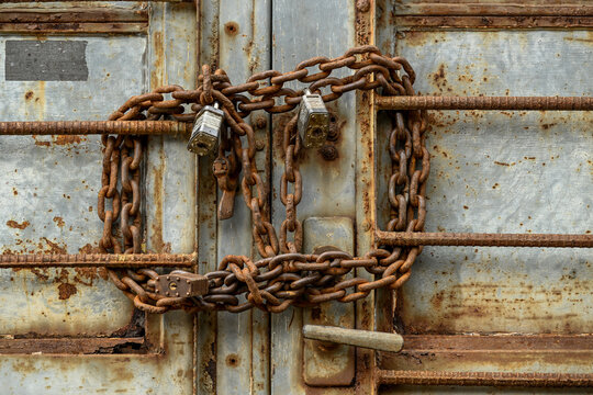 Close Up Of Rusty Chains And Multiple Locks On Old Abandoned Warehouse Door