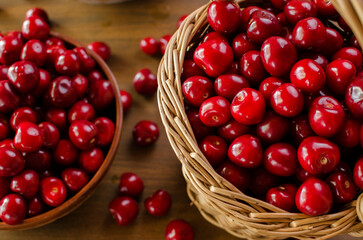 Red ripe cherries in a wicker basket still life on a wooden table. Flat lay, top view. Background