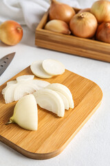 Wooden board with cut onion on light background, closeup