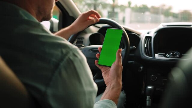 Male driver using a smartphone inside the car. Chromakey smartphone with green