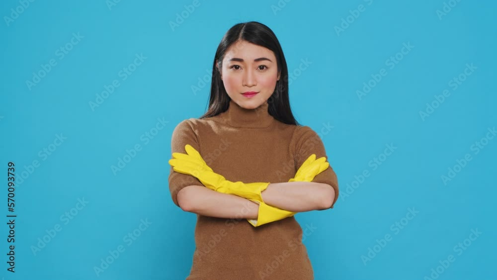 Wall mural asian professional maid smiling at camera after finishing house cleaning, standing in studio over bl