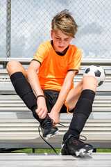 Youth soccer player having trouble tying his cleats