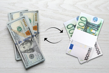 Currency exchange. Circle arrows between dollars and euro banknotes on white wooden background, flat lay