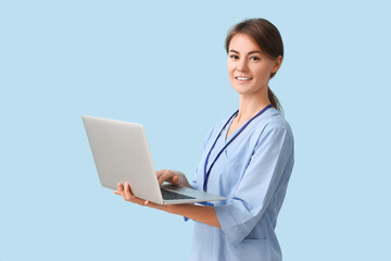 Female medical intern using laptop on blue background