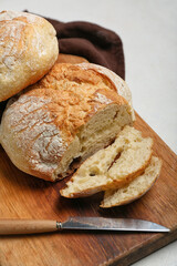 Cutting board with sliced loaf of fresh bread on white table