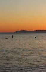 Silhouetted against the fiery hues of the setting sun, a fleet of boats rests on the horizon. The tranquil waters mirror the colorful sky, creating a breathtaking symphony of light and reflection.