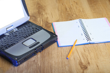 laptop next to a notebook with a pen