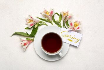Cup of tea, alstroemeria flowers and card with word SPRING on light background