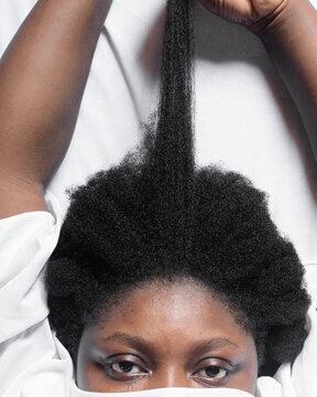 A woman stretching her curly hair to emphasize shrinkage, 4c hair stretched to show shrinkage