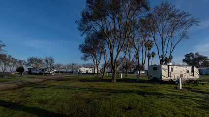 Trailer and Fifth Wheel trailers parked at campsite under blue skies