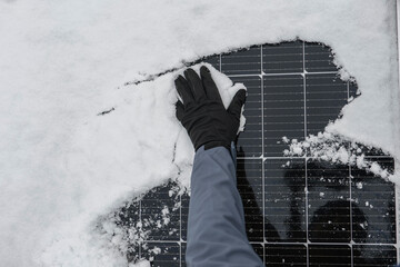 Solar energy in winter time.Getting electricity with solar panels in winter.Hands in black gloves...