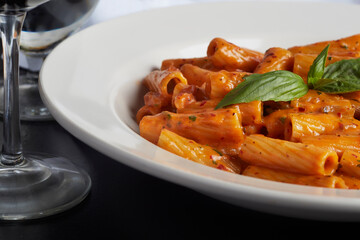 Classic Penne all Vodka. Italian ziti pasta covered in sauce garnished with a sprig of basil. White...