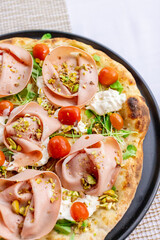 Neapolitan pizza with ham, arugula and cherry tomato