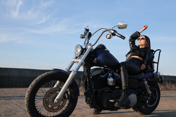 Fototapeta na wymiar Beautiful young woman posing on motorcycle outdoors