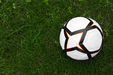 Fototapeta na wymiar New soccer ball on fresh green grass outdoors, top view. Space for text