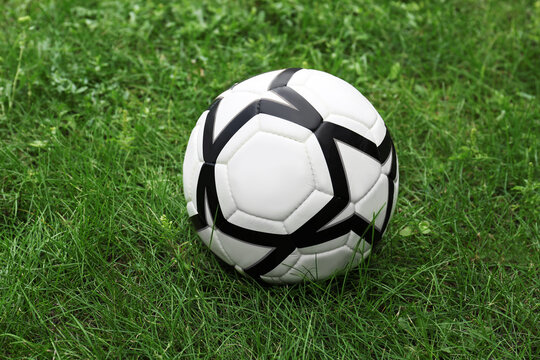 New soccer ball on fresh green grass outdoors