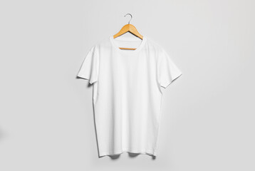 Hanger with white t-shirt on light wall. Mockup for design