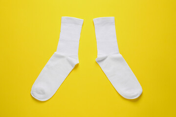 Pair of white socks on yellow background, flat lay