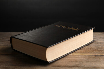 Bible with dark cover on wooden table. Christian religious book
