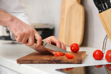 Obraz na płótnie Canvas Professional chef cutting tomatoes in kitchen, closeup