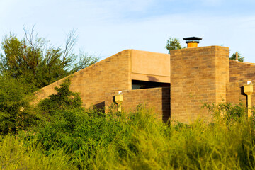 Brick building exterior with chimneys and visible windows on side of house or home in desert landscape sunset cactuses