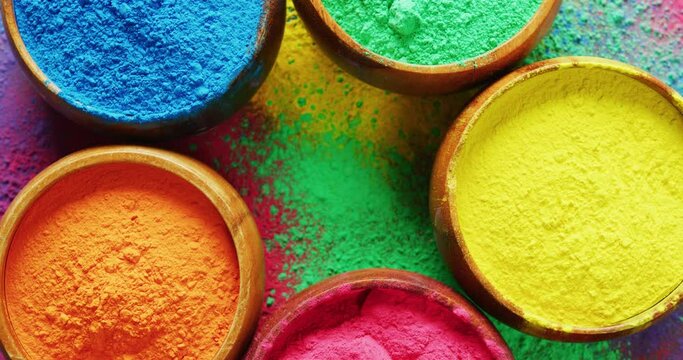 Video of close up of multi coloured powders in bowls with copy space on black background