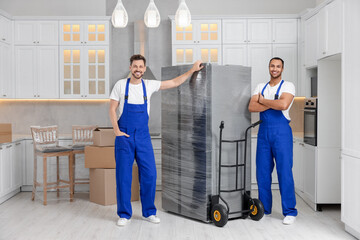 Fototapeta na wymiar Male movers with refrigerator in new house