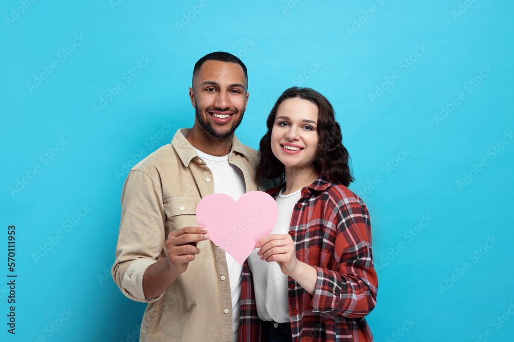 Poster Lovely couple with pink paper heart on light blue background. Valentine's day celebration