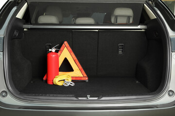 Red fire extinguisher, towing strap and foldable emergency warning triangle in trunk, space for...