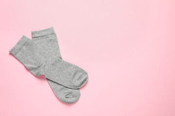 Pair of grey socks on pink background, flat lay. Space for text