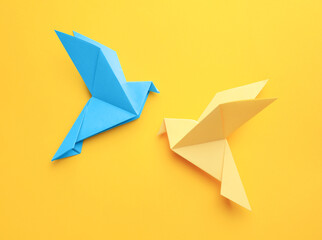 Origami art. Colorful handmade paper birds on yellow background, flat lay