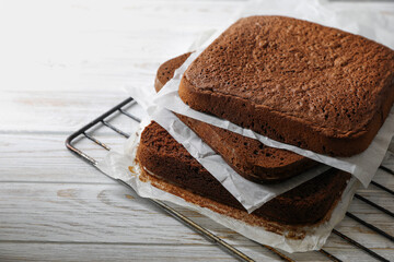Layers of homemade chocolate sponge cake on white wooden table, closeup. Space for text