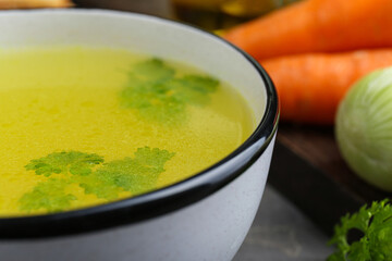 Delicious chicken bouillon with parsley on grey table, closeup