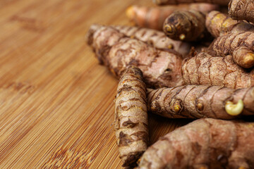 Many whole turmeric roots on wooden table, closeup. Space for text