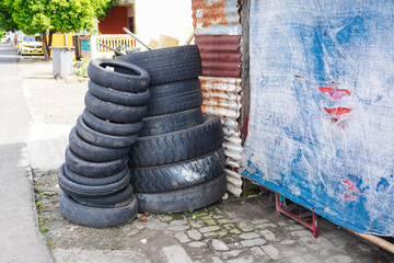 A large pile of used car tires lies on the side of the road. Environmental pollution problem