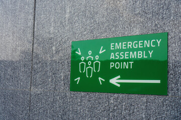 Emergency sssembly point sign on the textured wall. Assemble here for safety
