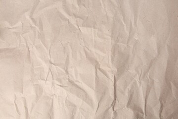 Sheet of crumpled light brown paper as background, top view