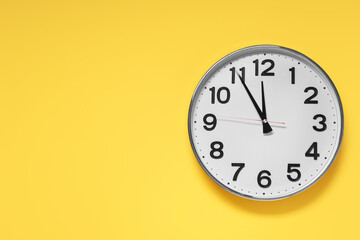 Clock showing five minutes until midnight on yellow background, top view with space for text. New...