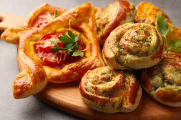 Different delicious puff pastry with tasty filling on wooden board, closeup