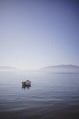 Small boat floating on the empty quiet sea. Concept of calm and serenity.