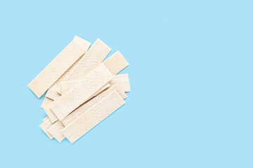 Many sticks of tasty chewing gum on light blue background, flat lay. Space for text