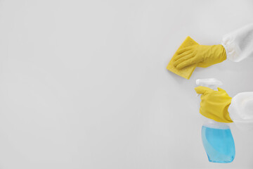 Woman in protective suit cleaning mold with sprayer and rag on wall, closeup. Space for text