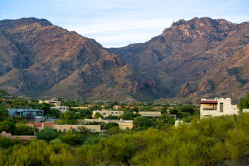 Fototapeta na wymiar Towering moutains in a hillside desert neighborhood with houses and homes in arizona in early morning shade