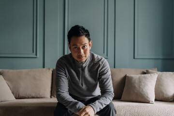 Fototapeta premium Asian man in fleece sitting in the living room in cold weather.