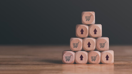wooden blocks stacked on the table, shopping carts and arrows representing sales or business growth, Online shopping concept, e-commerce, online store ,SME, Startup or small business entrepreneur