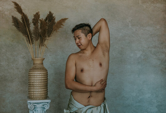 Chinese man with scar stretching next to roman column