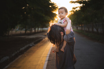 Beautiful Mother And Baby outdoors in sun light.  Beauty Mum and her Child playing in Park together,Outdoor Portrait of happy family. Mom and Baby