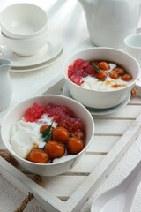 two bowls of sweet porridge and starch balls with brown sugar sauce and coconut milk close up